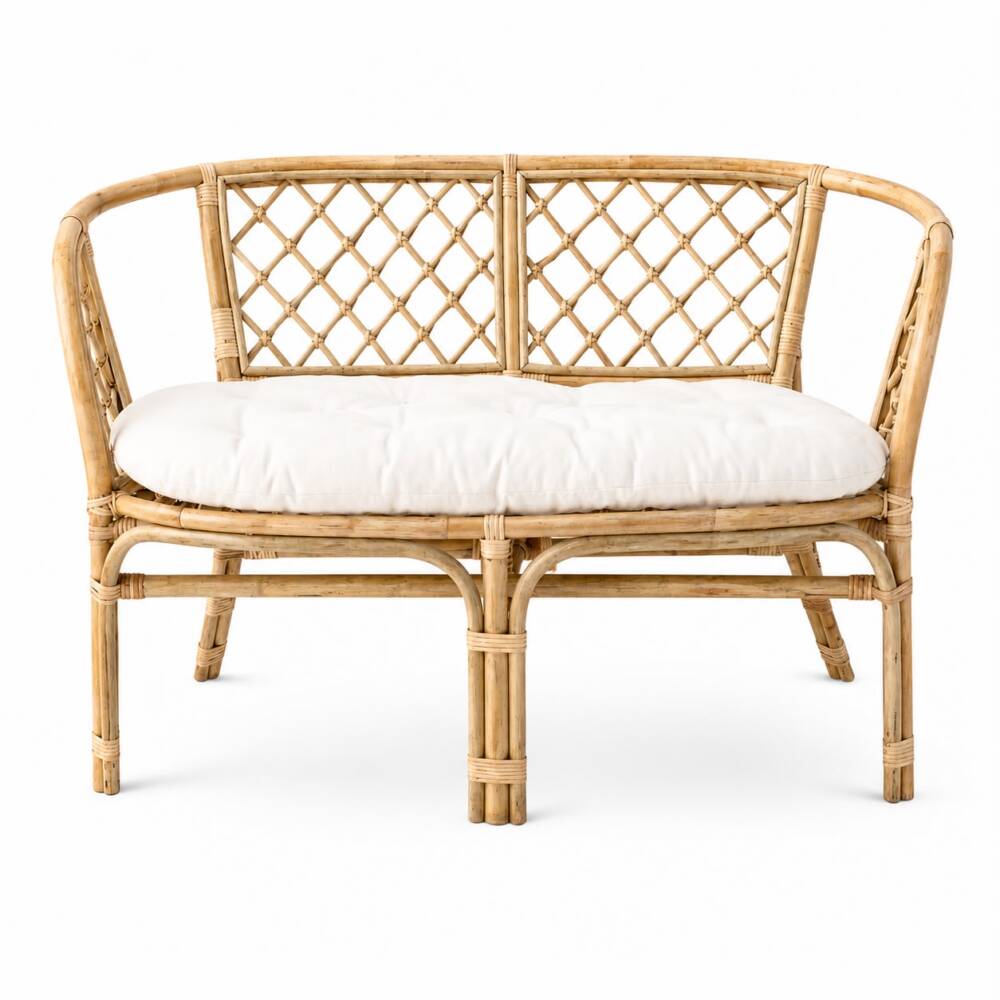 A natural rattan two-seater sofa with a tufted white seat cushion and a decorative lattice pattern backrest.